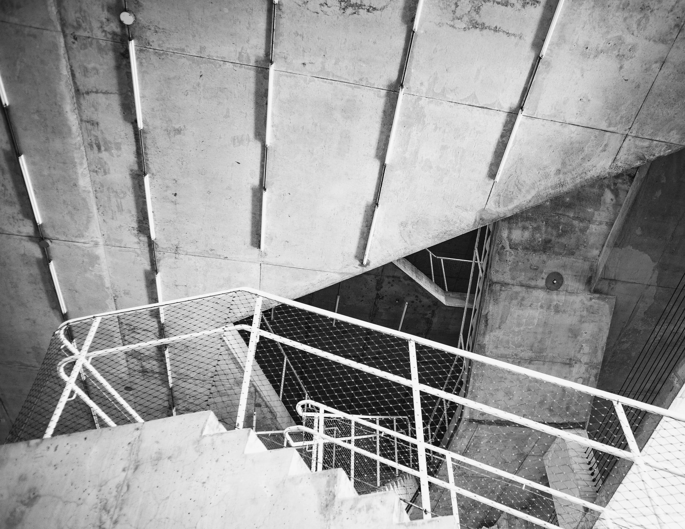 Escalera de hormigón visto con baranda blanca, vista desde arriba